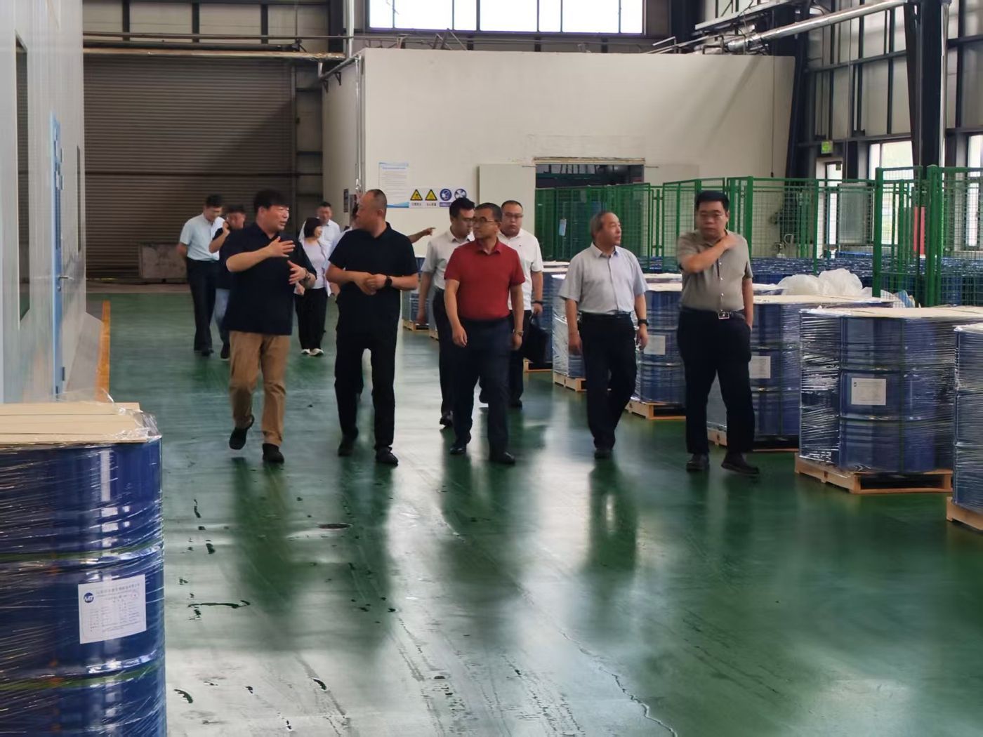 Delegation reviews drum storage and batch labeling in the warehouse